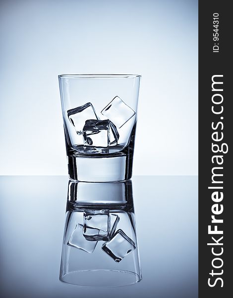 Tall tumbler filled with ice placed on a wet metallic tabletop. Tall tumbler filled with ice placed on a wet metallic tabletop.