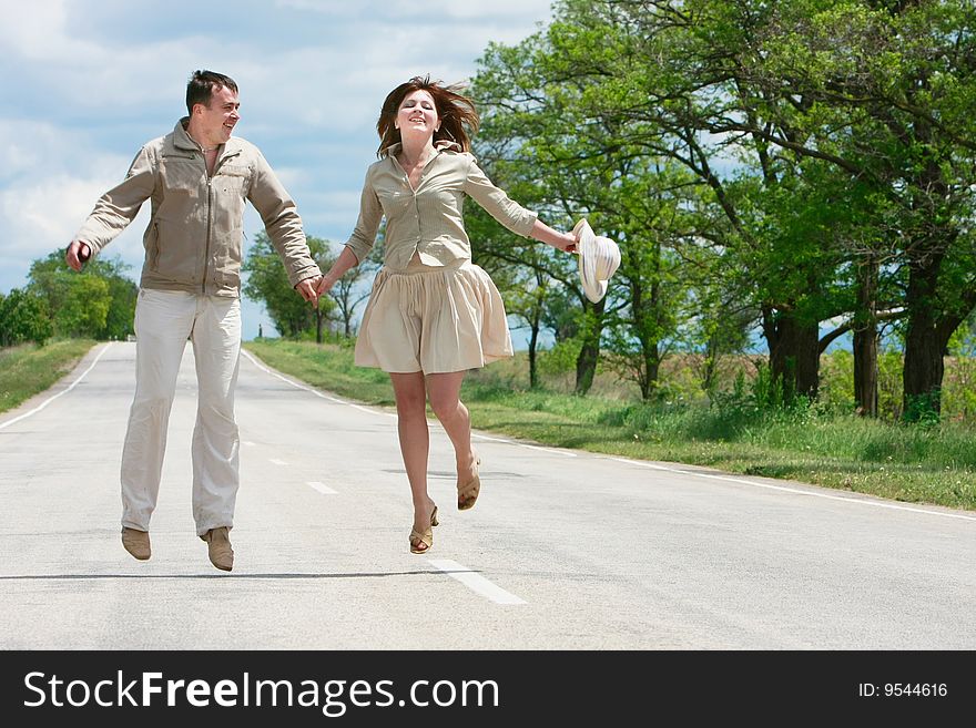 Happy couple jumping on rural road