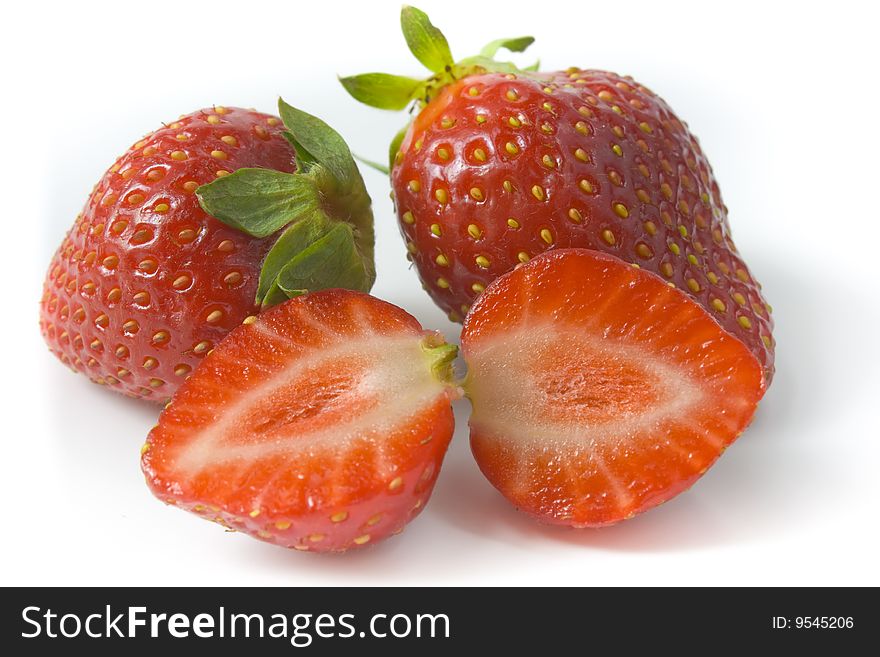 Two ripe strawberries and two segments of a strawberry. A photo close up.