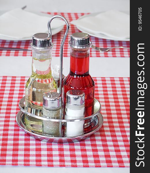 Plait with silverware and spices on table with red checked tablecloth. Plait with silverware and spices on table with red checked tablecloth