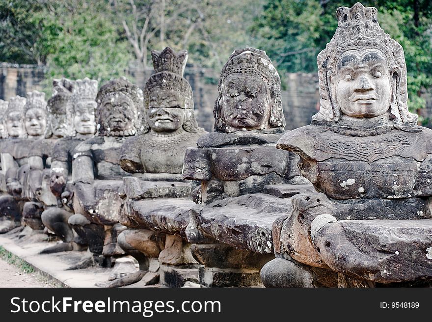 Broken statues line one of the bridges in the Angkor Wat temple ground in Siem Reap, Cambodia. this popular tourist destination sees many travelers making the journey to see these old ruins from hindu and buddhist backgrounds. Broken statues line one of the bridges in the Angkor Wat temple ground in Siem Reap, Cambodia. this popular tourist destination sees many travelers making the journey to see these old ruins from hindu and buddhist backgrounds.