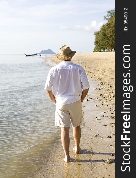 Handsome man strolling along a beautiful beach on an island. Handsome man strolling along a beautiful beach on an island