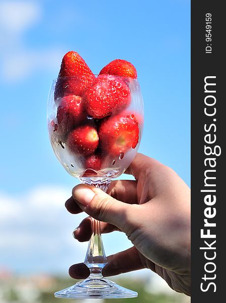 Fresh, sweet strawberry in glass over blue sky