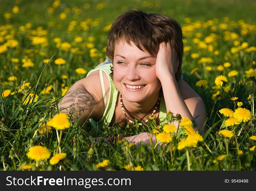 A young cheerful woman having fun on a dandelions glade