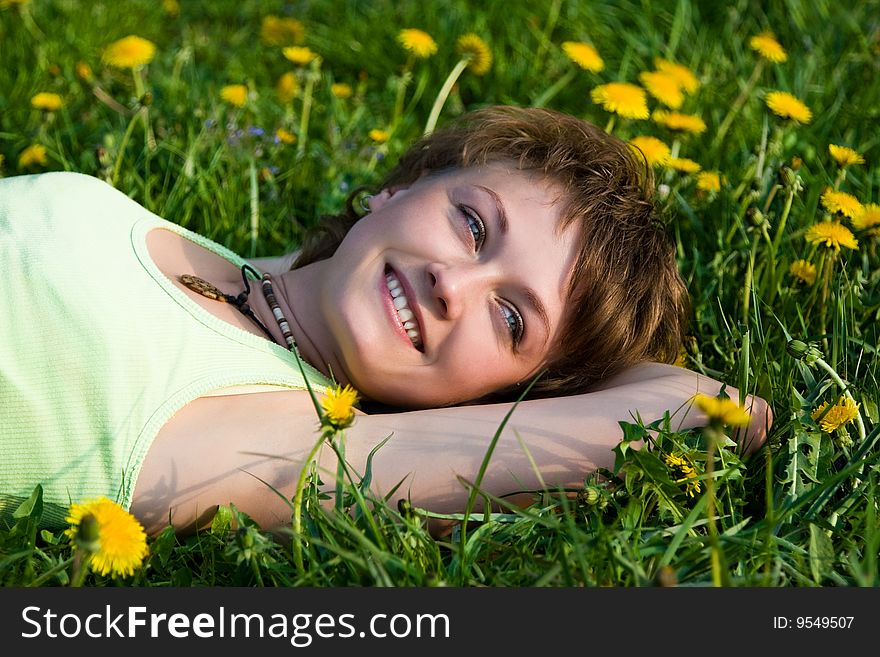 A young cheerful woman having fun on a dandelions glade