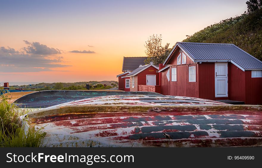 Red rustic houses in field at sunset. Red rustic houses in field at sunset.