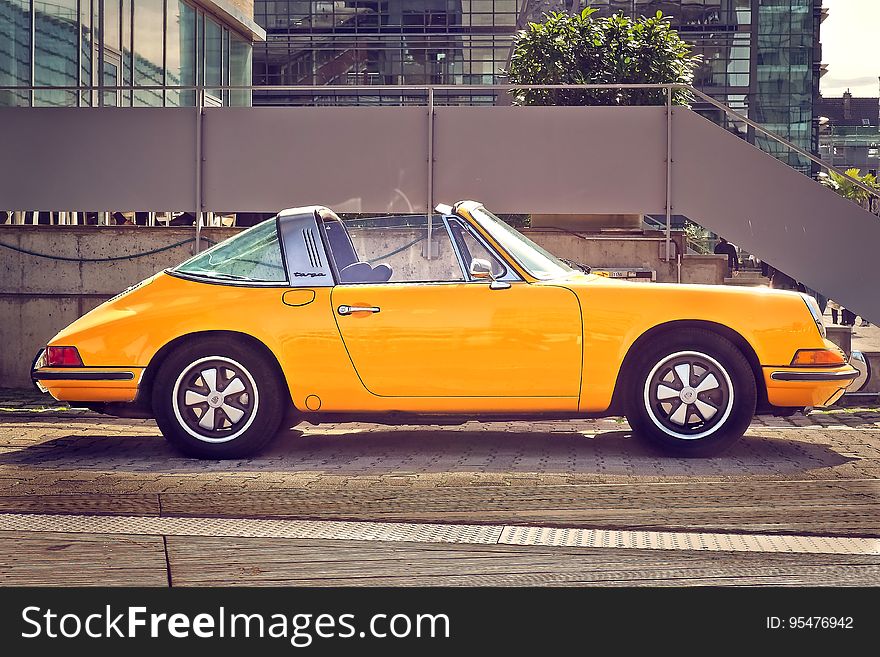 Side view of yellow Porsche 911 AG motor car parked on sidewalk in city. Side view of yellow Porsche 911 AG motor car parked on sidewalk in city.