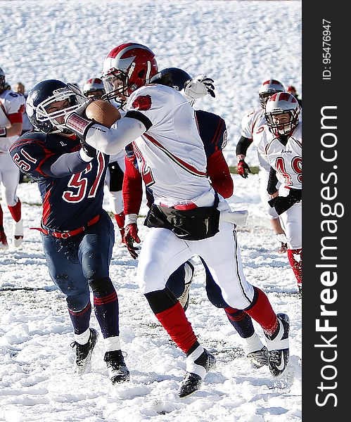 Football players during game being played on snowy field on sunny day. Football players during game being played on snowy field on sunny day.