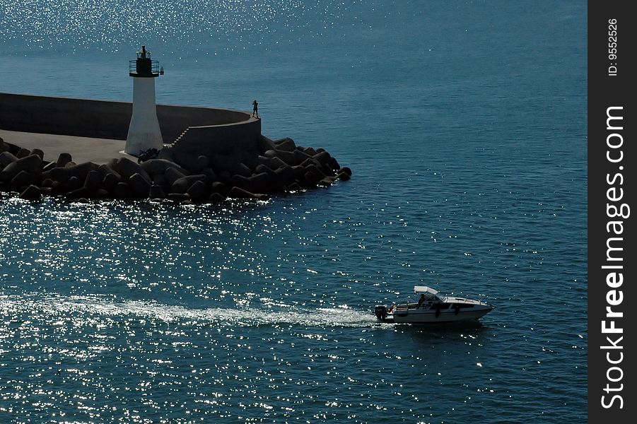 Little boat sailing in glittering sea, man observing from the pier. Little boat sailing in glittering sea, man observing from the pier.