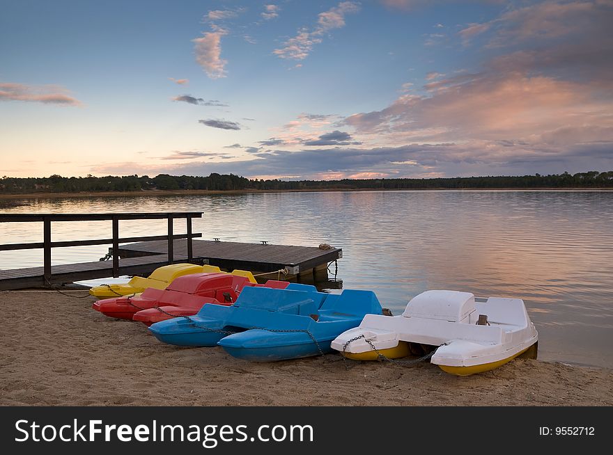 Pedal boats of various colors lined up at lake bank