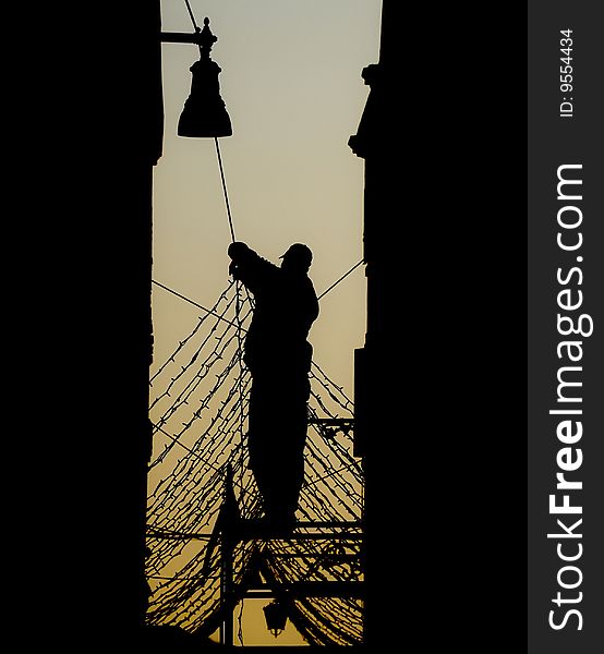 Silhouette of a man fixing street decorations