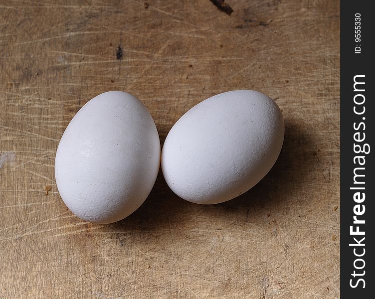 Two white eggs on a wooden table