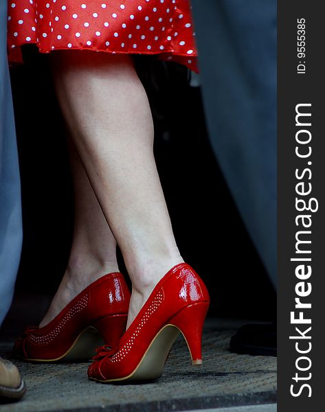 A woman's legs wearing red shoes