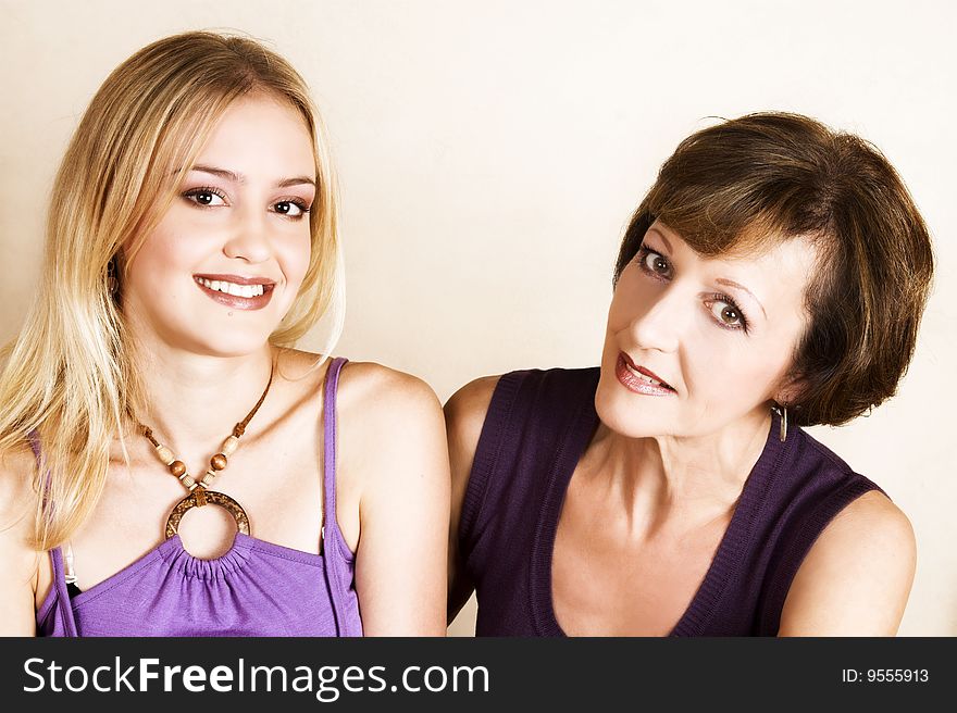Beautiful mother and daughter against a light background