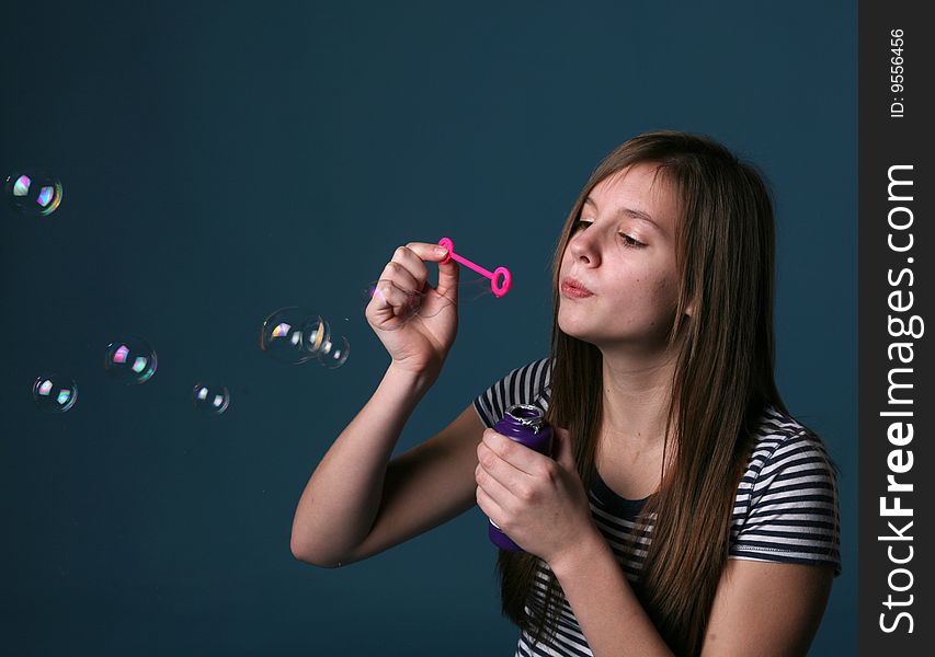 Pretty girl in striped shirt blowing bubbles. Pretty girl in striped shirt blowing bubbles