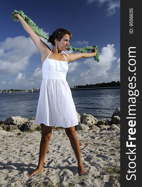 Beautiful woman in white dress stretching at the beach. Beautiful woman in white dress stretching at the beach