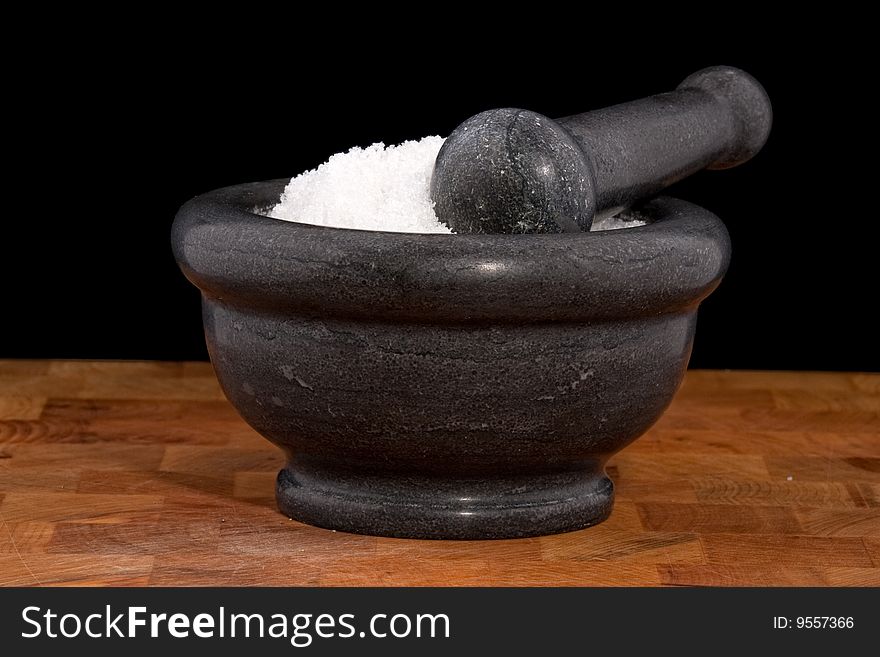 Mortar and pestle with salt, fleur de sel, black background