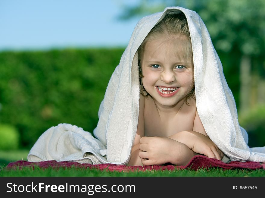 Young child is lying on lawn with towel on head. Young child is lying on lawn with towel on head