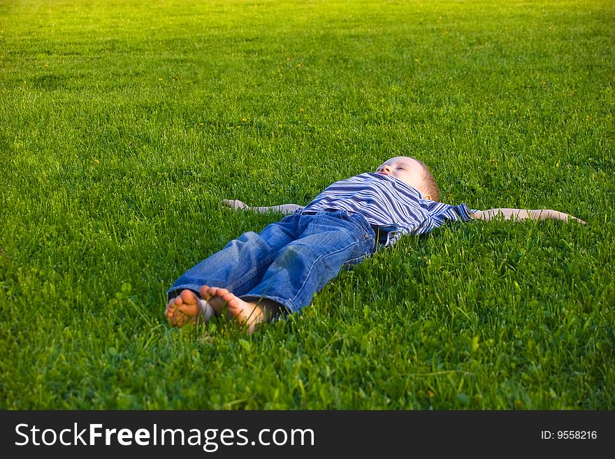 The four-year boy lies on a grass