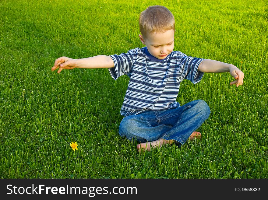 The four-year boy sits on a grass crossing legs. The four-year boy sits on a grass crossing legs