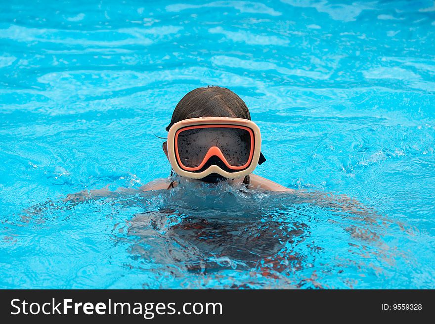 A young boy in pool with goggles on. A young boy in pool with goggles on