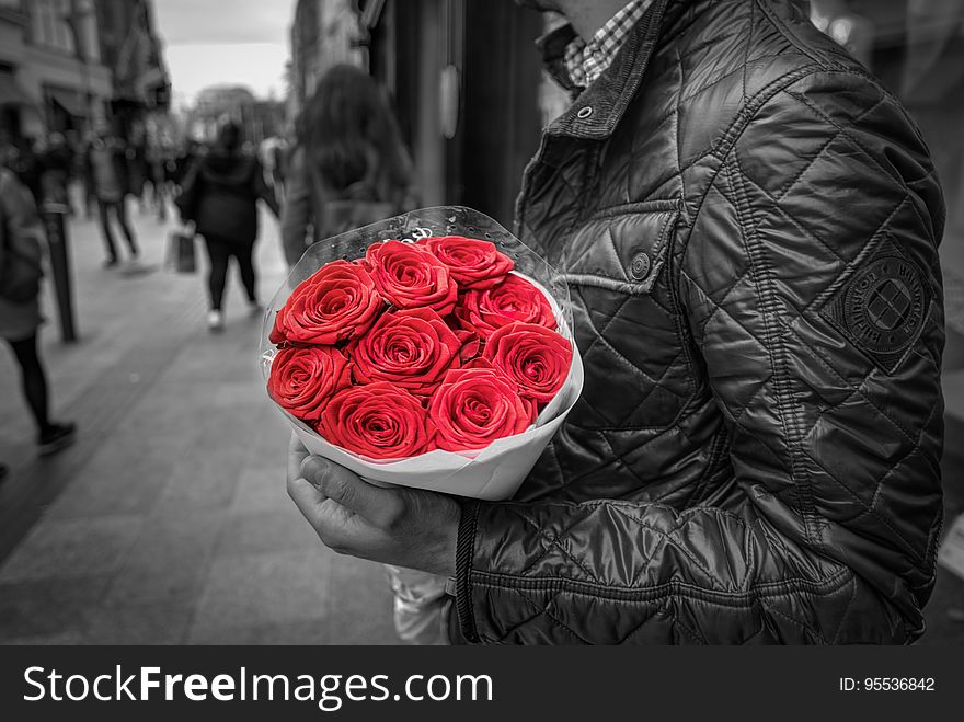 A man in a jacket holding a red rose bouquet. A man in a jacket holding a red rose bouquet.