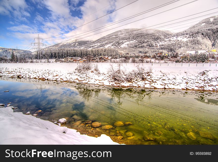Utility stanchions through snow covered mountain landscape reflecting in small stream on sunny day. Utility stanchions through snow covered mountain landscape reflecting in small stream on sunny day.