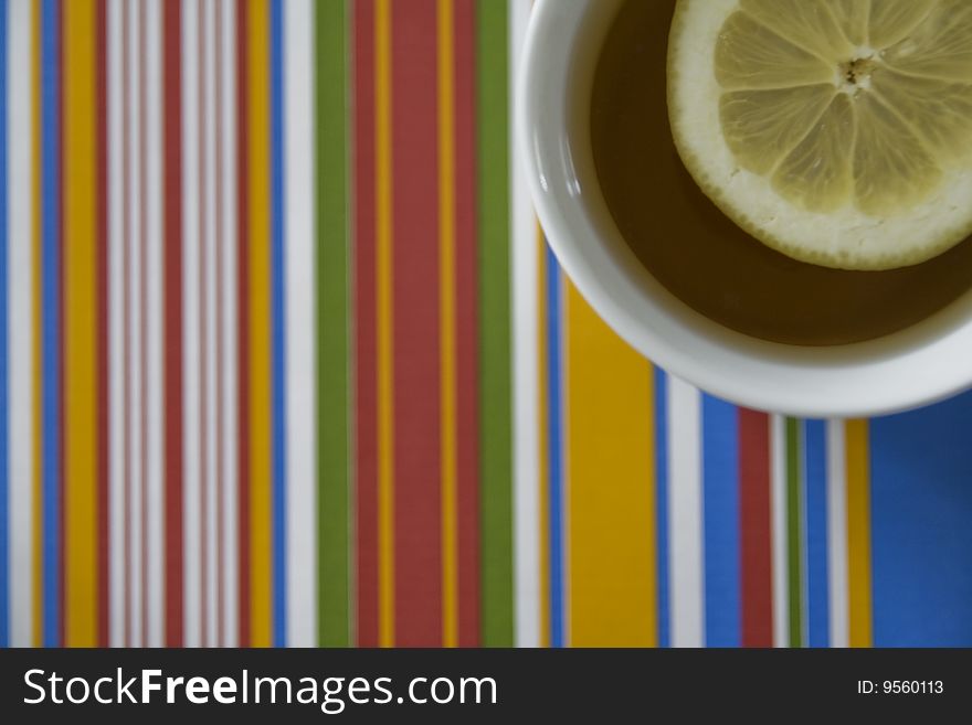 Tea with a slice of lemon on a nice and very colourful striped background, looks very retro. Tea with a slice of lemon on a nice and very colourful striped background, looks very retro.