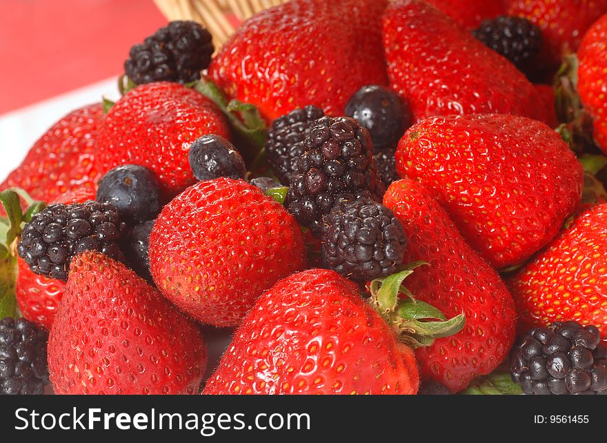 Freshly picked strawberries, blackberries and blueberries spilling out of a basket. Freshly picked strawberries, blackberries and blueberries spilling out of a basket