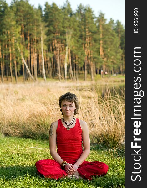 A young pretty woman sitting in pose on the forest background. A young pretty woman sitting in pose on the forest background