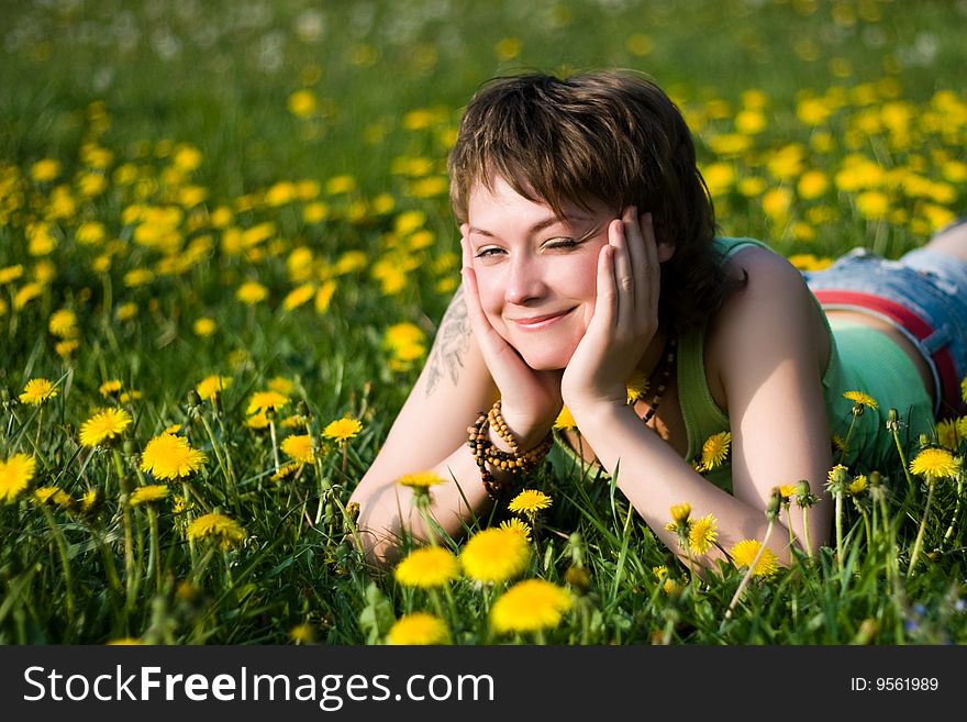 A young cheerful woman having fun on a dandelions glade