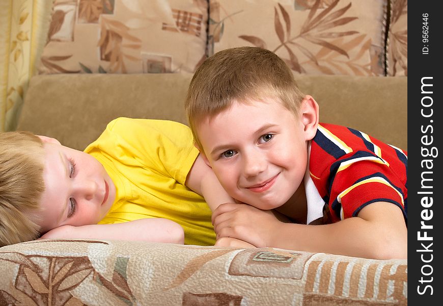 Portrait of two boys laying on a sofa of the house