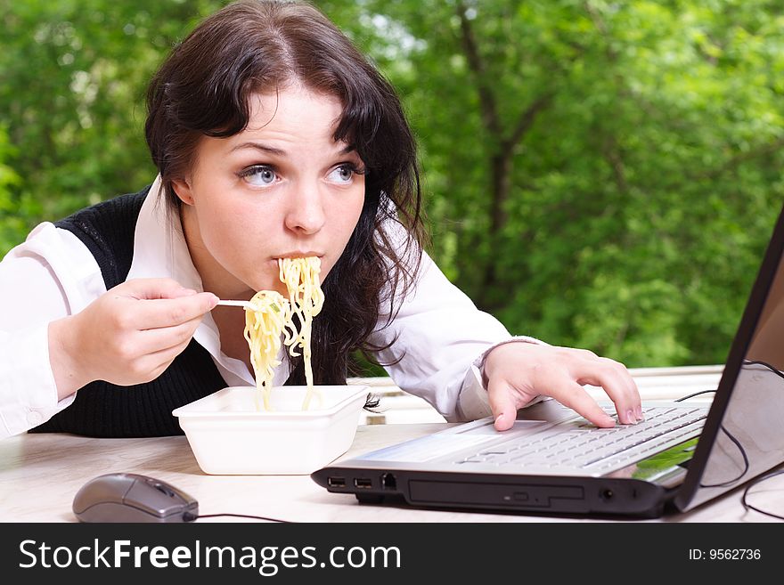 Young girl eats noodles and looks in the monitor. Young girl eats noodles and looks in the monitor