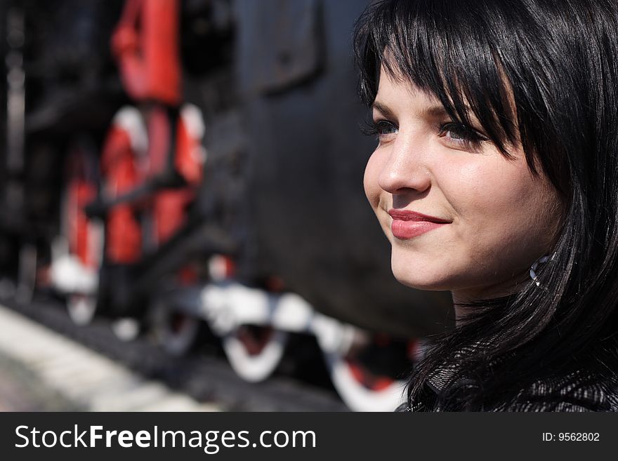 Portrait of the girl on a background of wheels of a steam locomotive. Portrait of the girl on a background of wheels of a steam locomotive