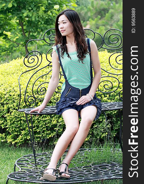 A modern asian girl is sitting in the chair outdoors. A modern asian girl is sitting in the chair outdoors.