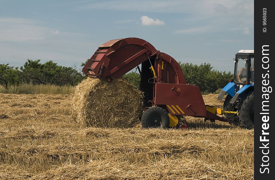 Tractor making straw rolls. Agriculture concept