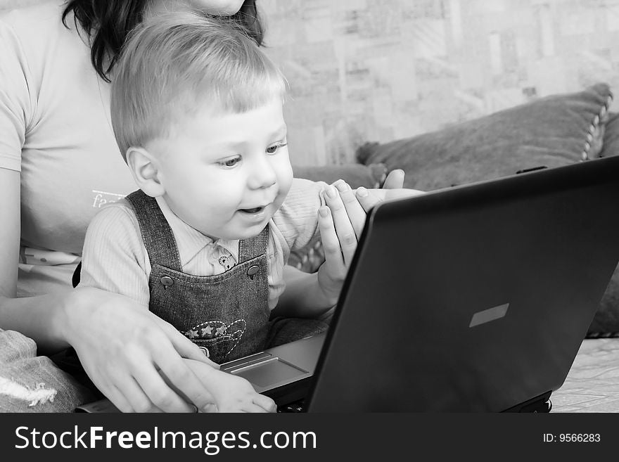 The small beautiful boy together with mum looks smiling on the screen laptop. The small beautiful boy together with mum looks smiling on the screen laptop