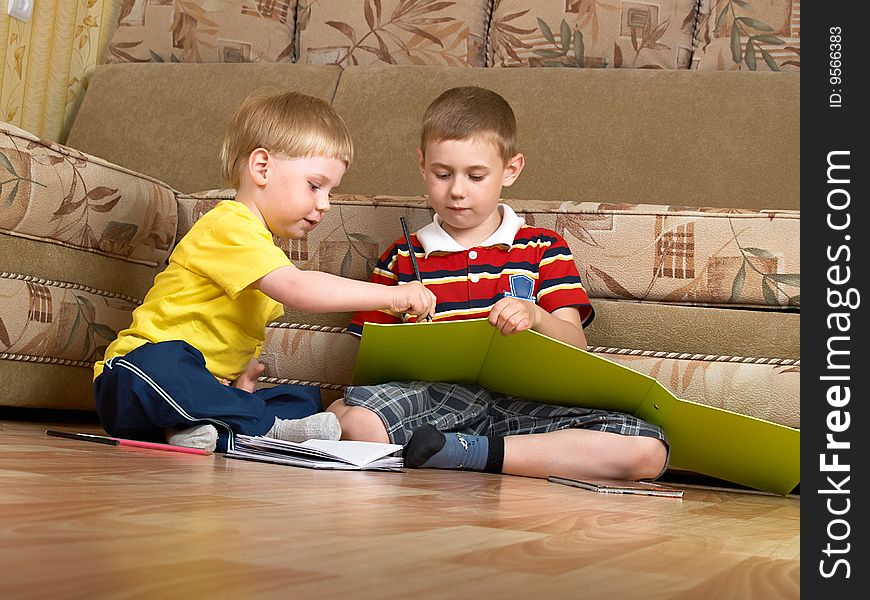 Two boys draw with paints sitting on floor