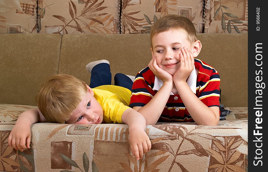 Portrait of two boys laying on a sofa of the house