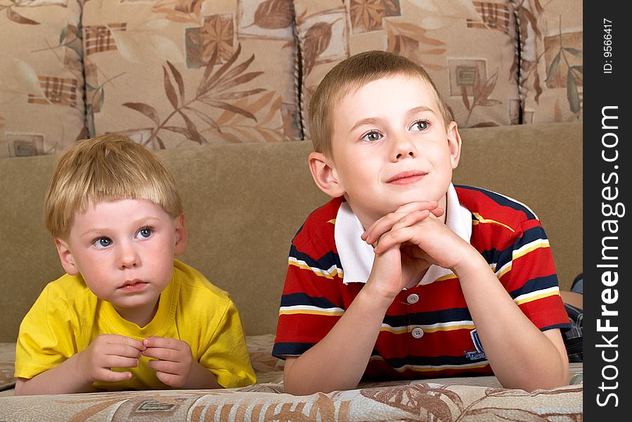 Portrait of two boys laying on a sofa of the house