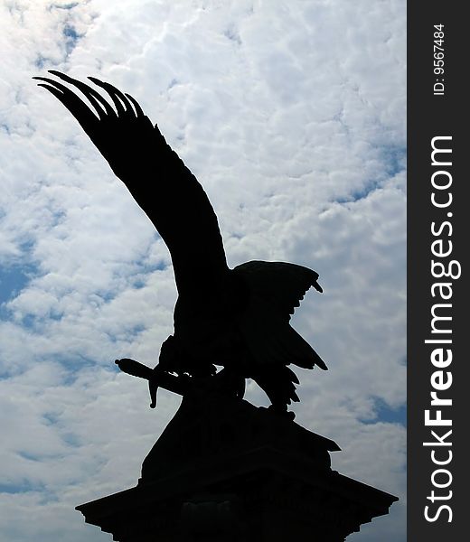 Black silhouette of eagle statue on cloudy sky background