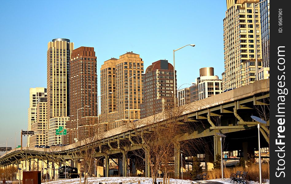 An urban landscape in NYC with a raised highway and tall residential and commercial buildings in the background.