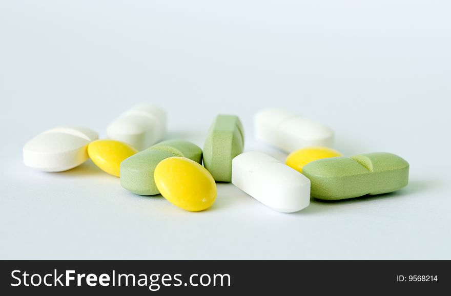 Tree yellow and green tablets and four white pills. Tree yellow and green tablets and four white pills
