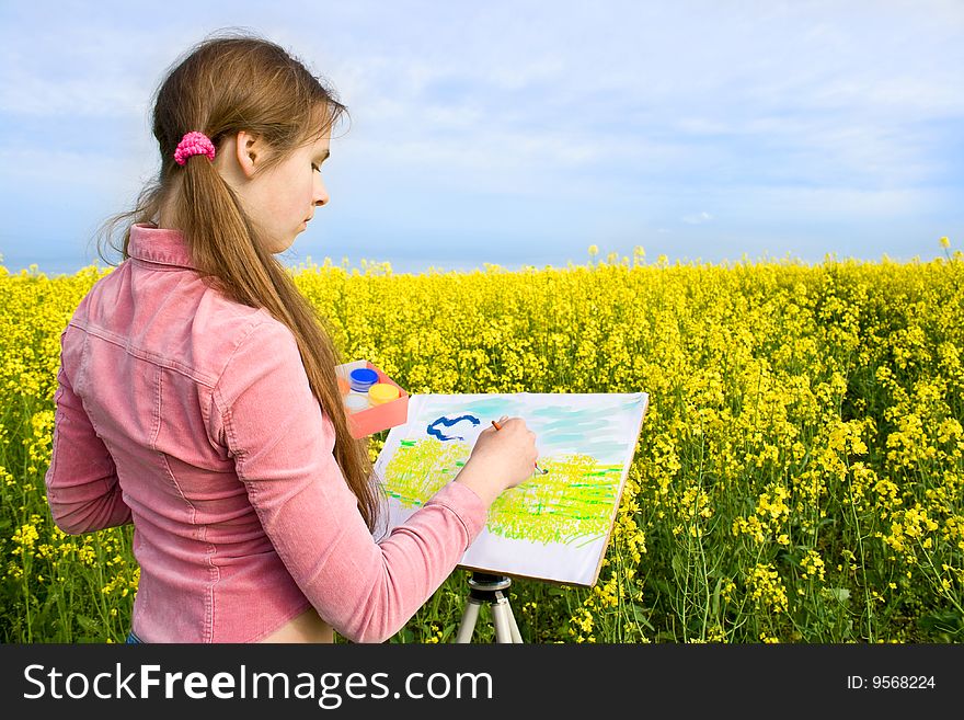 The girl with enthusiasm draws paints on a paper a landscape. The girl with enthusiasm draws paints on a paper a landscape.