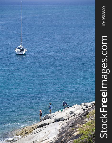 Beautiful yacht in the ocean and fishermen on the rocks. copy space. Beautiful yacht in the ocean and fishermen on the rocks. copy space