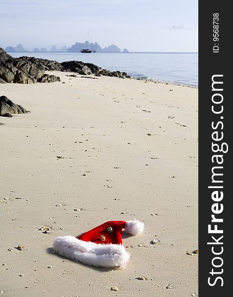 A red Christmas hat with fur and bells on the beach. A red Christmas hat with fur and bells on the beach