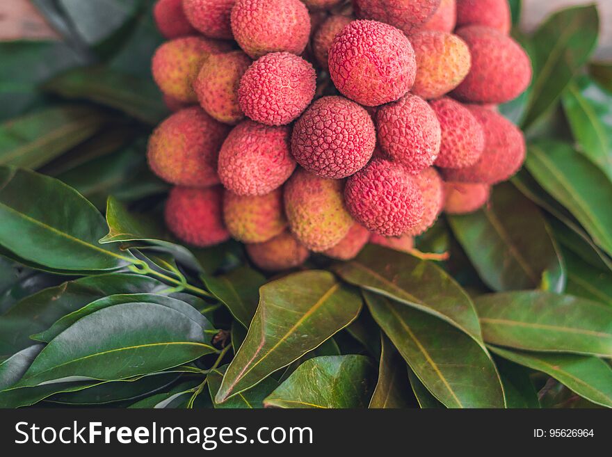 Fresh Organic Lychee Fruit And Lychee Leaves On A Rustic Wooden Background