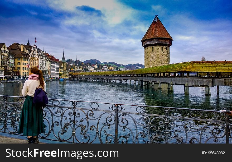 Woman standing on railing by lake in Switzerland on sunny day. Woman standing on railing by lake in Switzerland on sunny day.