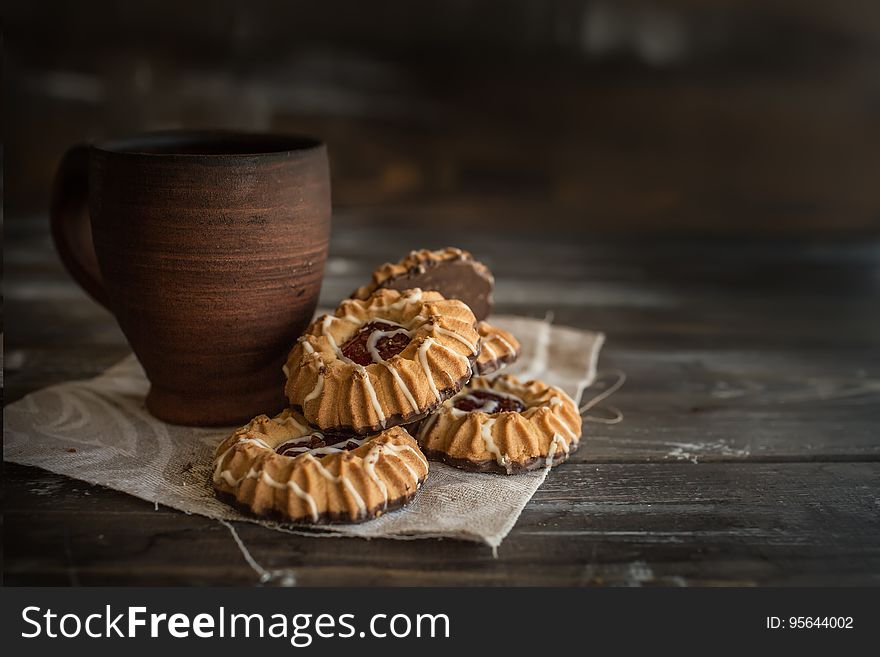 Close up of cookies on napkin next to rustic pottery mug on wooden table. Close up of cookies on napkin next to rustic pottery mug on wooden table.