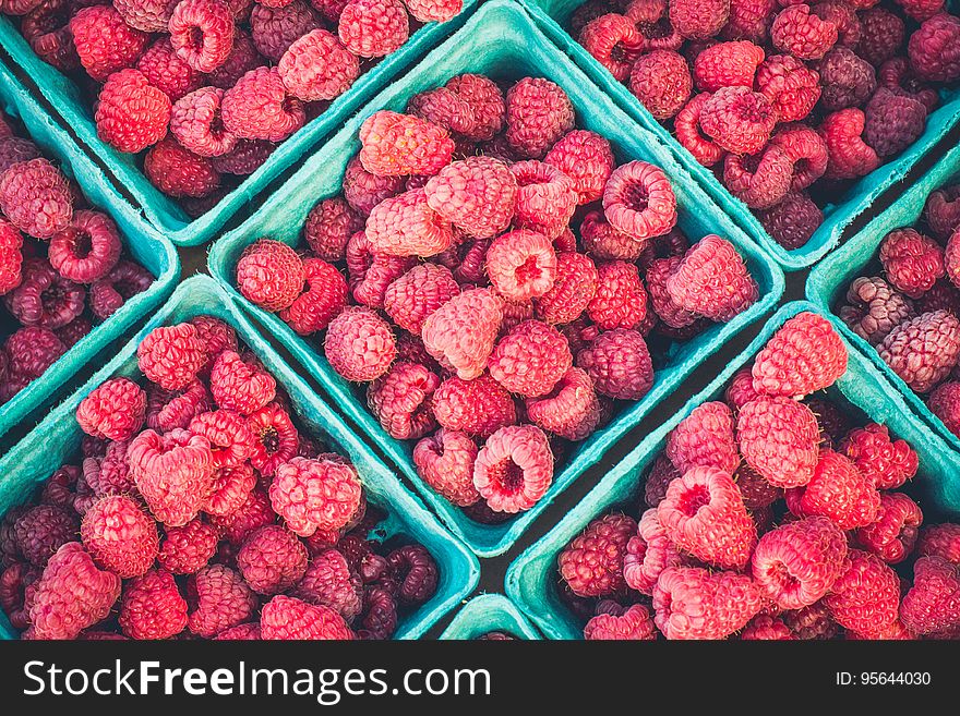 Close up of fresh red raspberries in green baskets in sunny market. Close up of fresh red raspberries in green baskets in sunny market.
